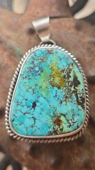 Blue-green polychromatic webbed blackjack pendant with sterling silver twist-wire trim and bail.